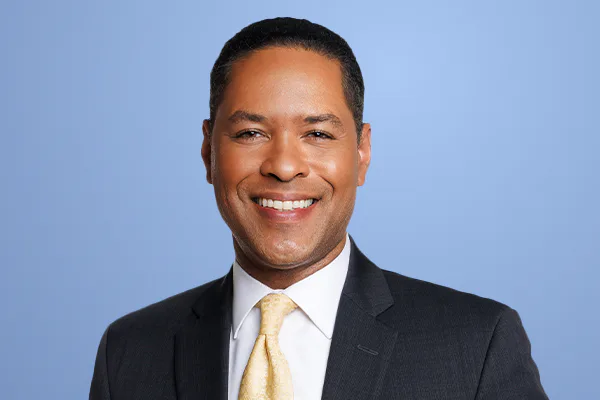 A portrait of journalist Rob Nelson smiling and wearing a suit.