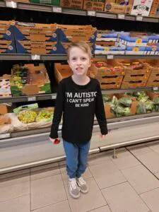 a picture of a smiling boy standing in a grocery store